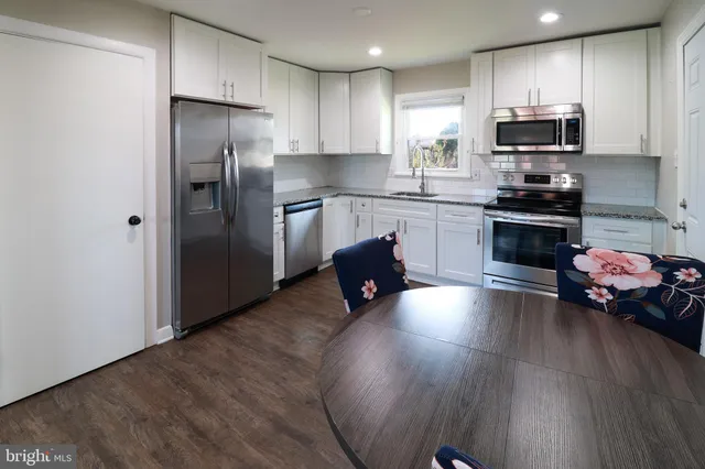 a kitchen with granite countertop a refrigerator and a stove top oven