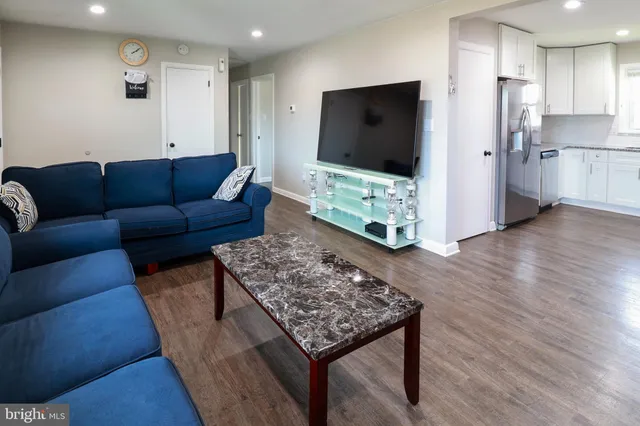 a living room with stainless steel appliances kitchen island granite countertop a couch and a flat screen tv