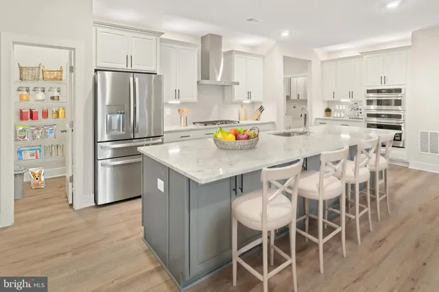 a kitchen with stainless steel appliances a refrigerator a stove a microwave and white cabinets with wooden floor