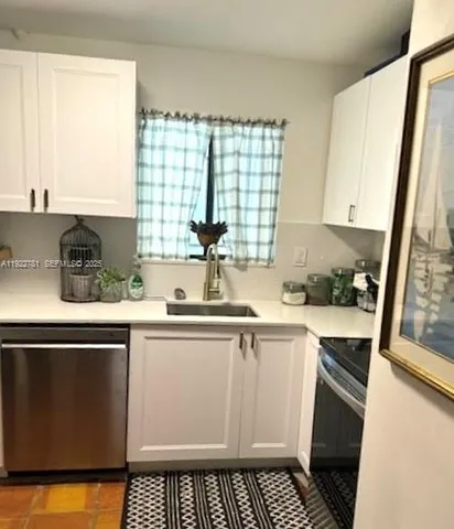 a white kitchen with sink and window