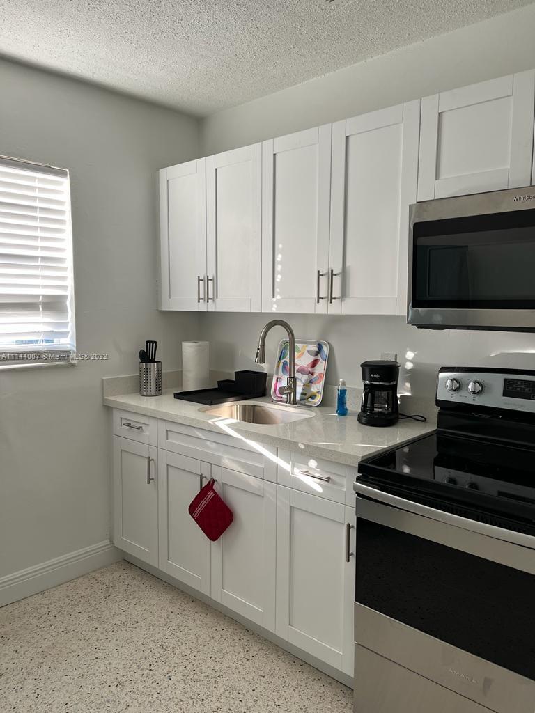 442 Southwest 9th Street, Unit 3 Miami, FL 33130 - Photo 2 of 10 a kitchen with stainless steel appliances granite countertop a stove a sink and a microwave