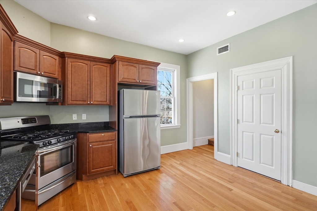 96 Washington Square East, Unit 2 Salem, MA 01970 - Photo 21 of 40 a kitchen with granite countertop wooden floors stainless steel appliances and cabinets