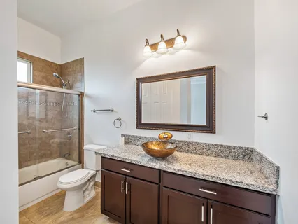a bathroom with a granite countertop sink toilet a mirror and shower
