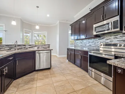 a kitchen with stainless steel appliances granite countertop a stove a sink and a microwave