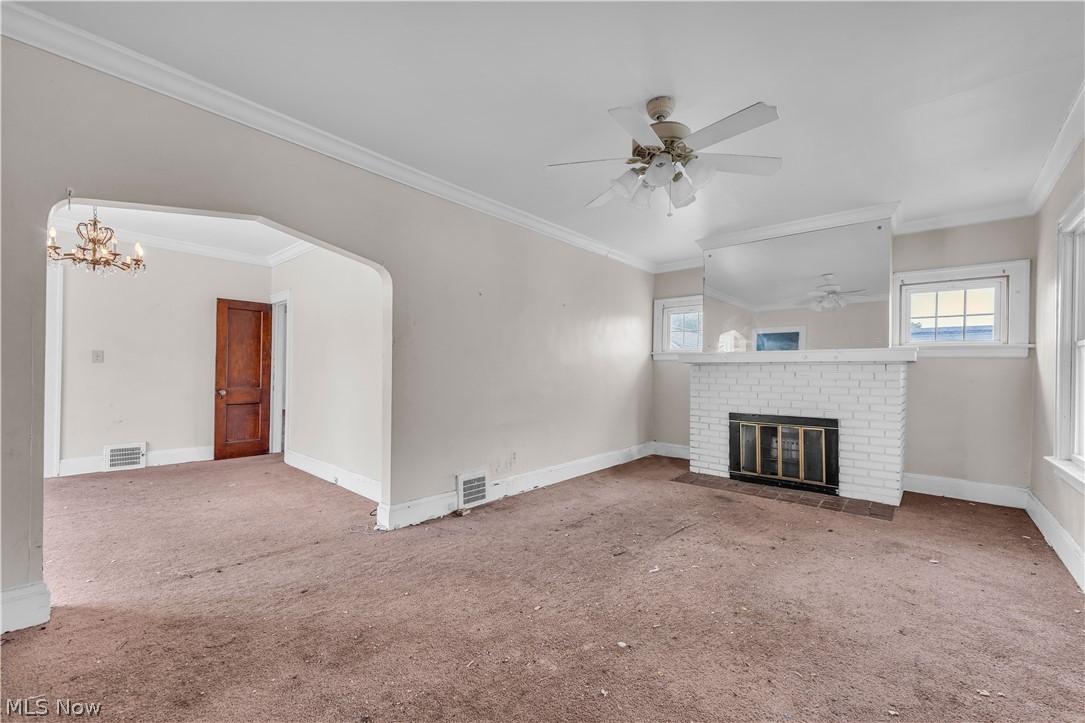 3713 Menlo Road Cleveland, OH 44120 - Photo 17 of 26 Unfurnished living room featuring a fireplace, carpet floors, ceiling fan with notable chandelier, and crown molding