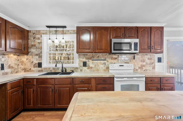 a kitchen with a stove a sink dishwasher and a refrigerator with wooden cabinets