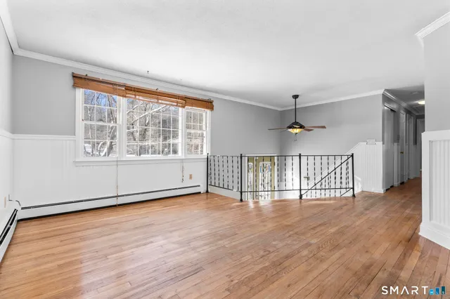 a view of a kitchen and an empty room with wooden floor
