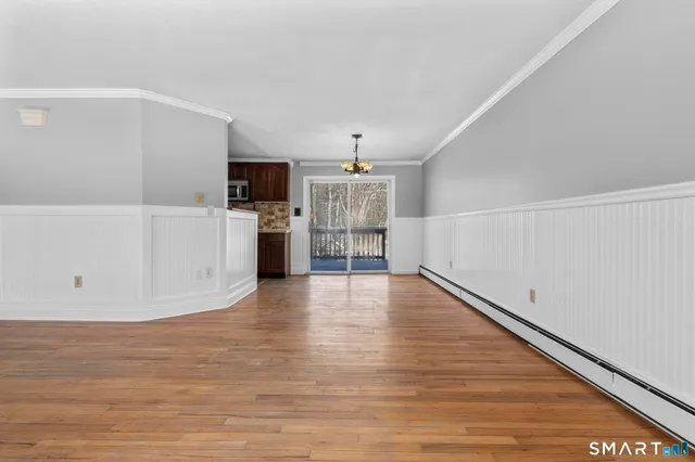 a view of a livingroom with furniture wooden floor chandelier and windows