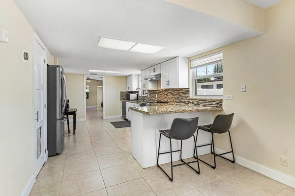 a kitchen with stainless steel appliances kitchen island granite countertop chairs and a refrigerator