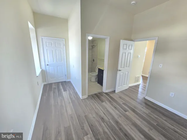 a view of a hallway with wooden floor and a bathroom