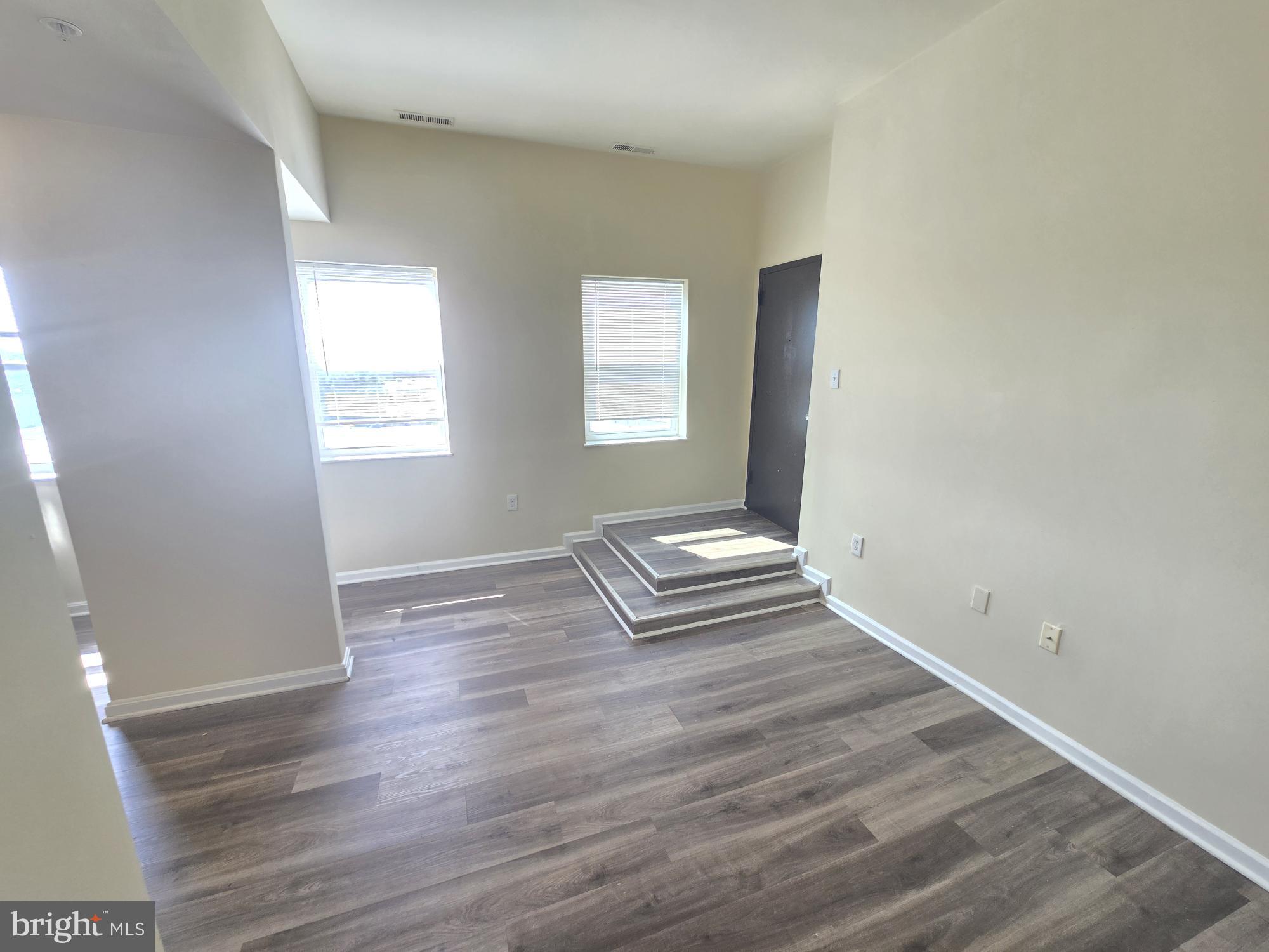 317 North Avenue East, Unit 112 Baltimore, MD 21202 - Photo 4 of 11 an empty room with wooden floor and windows