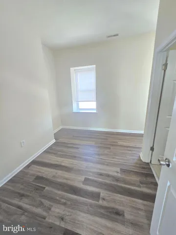 a view of an empty room with wooden floor and window