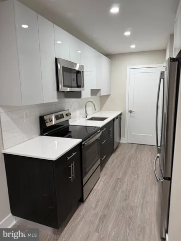 a kitchen with stainless steel appliances granite countertop a sink a stove a refrigerator and cabinets