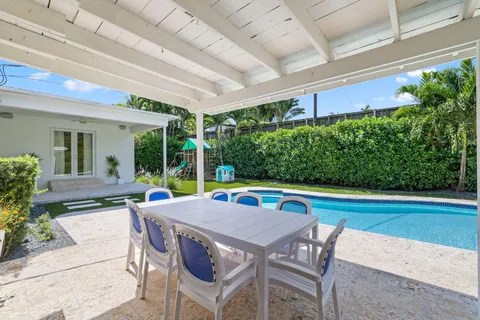 a view of backyard with table and chairs potted plants and large tree