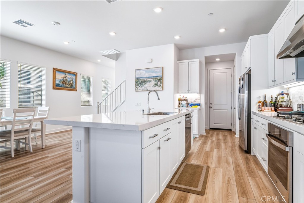 26767 Laurel Mountain Loop Valencia, CA 91381 - Photo 15 of 43 a large kitchen with stainless steel appliances a large counter top a stove a chimney a sink and a refrigerator
