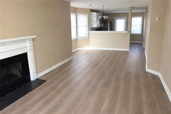 a view of a kitchen and an empty room with wooden floor and a kitchen