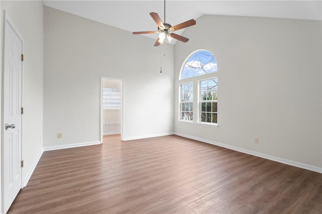 7815 Ridge Top Terrace Douglasville, GA 30134 - Photo 5 of 31 an empty room with wooden floor chandelier fan and windows