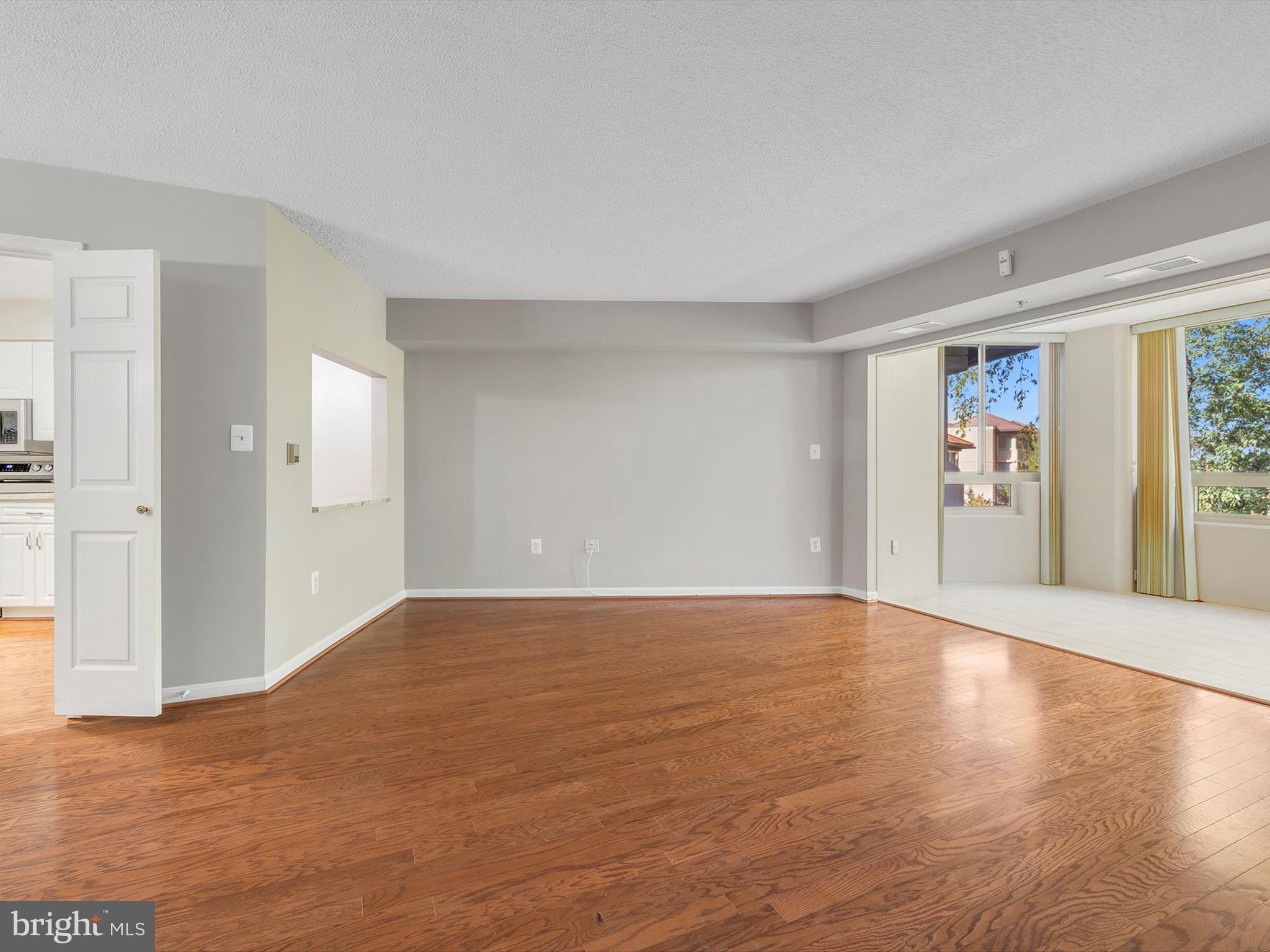 14809 Pennfield Circle, Unit 406 Silver Spring, MD 20906 - Photo 8 of 45 a view of an empty room with window and wooden floor