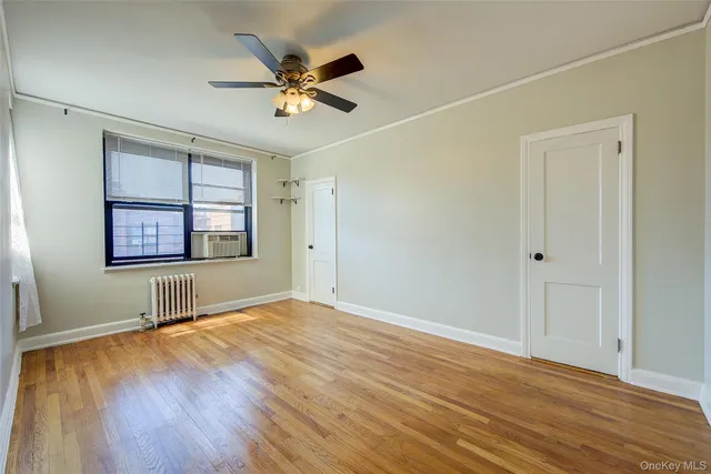 an empty room with wooden floor chandelier fan and windows