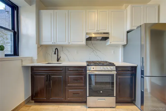 a kitchen with stainless steel appliances granite countertop a stove and a refrigerator with white cabinets