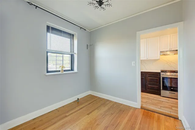 an empty room with wooden floor cabinet and windows