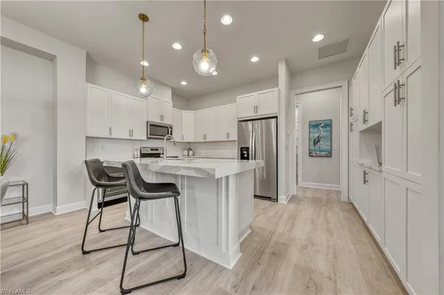a kitchen with stainless steel appliances kitchen island granite countertop a refrigerator a stove a sink a dining table and chairs with wooden floor