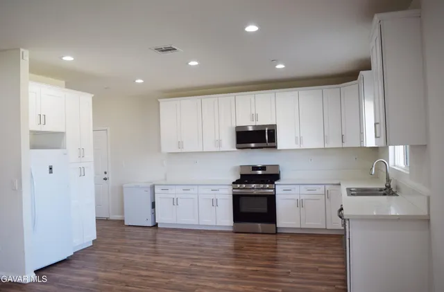 a kitchen with stainless steel appliances granite countertop a stove top oven a sink and a refrigerator