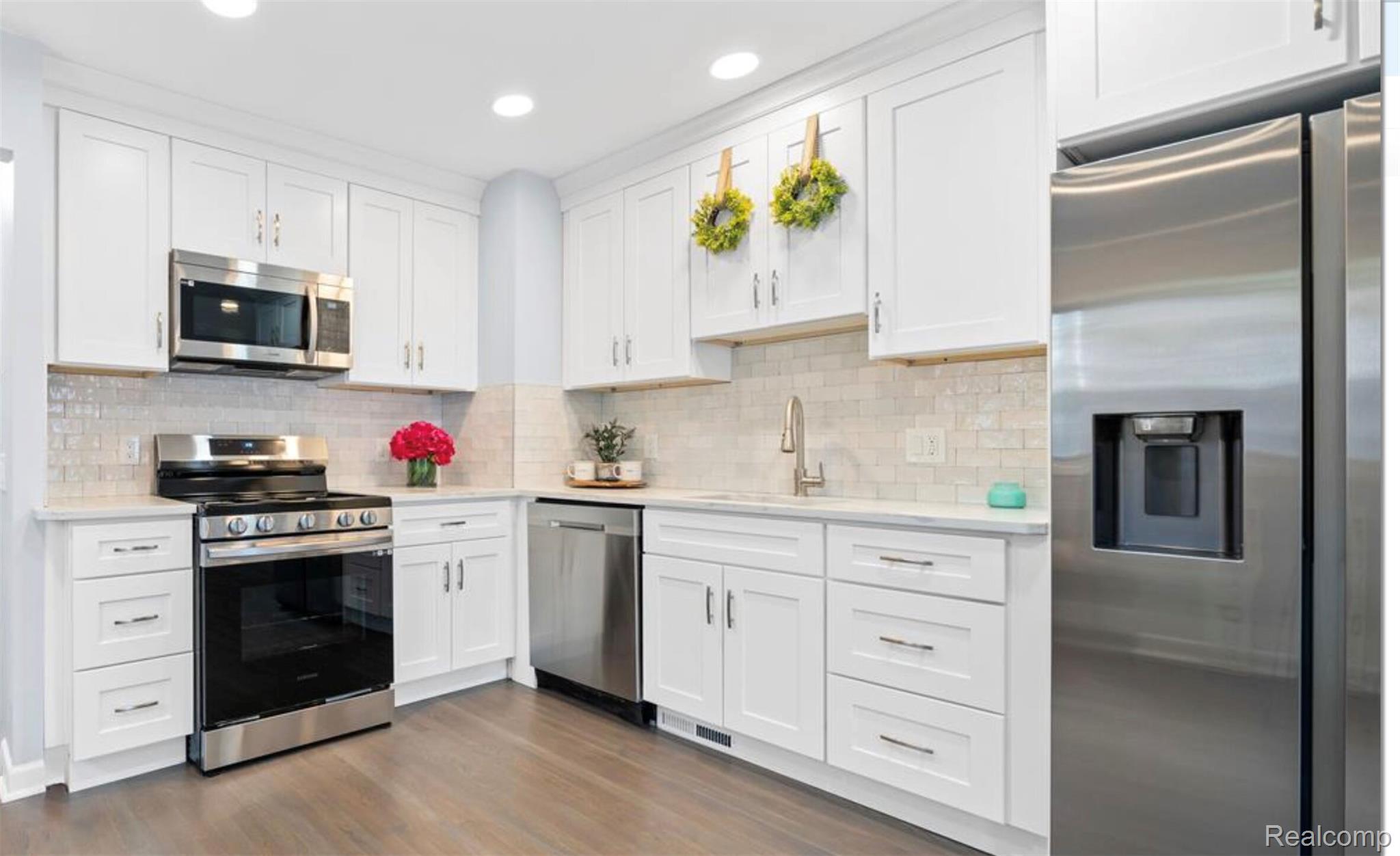 4214 Berkshire Road Royal Oak, MI 48073 - Photo 9 of 27 Kitchen featuring white cabinetry, stainless steel appliances, a tile backsplash, light-toned countertops, and wood-finish flooring