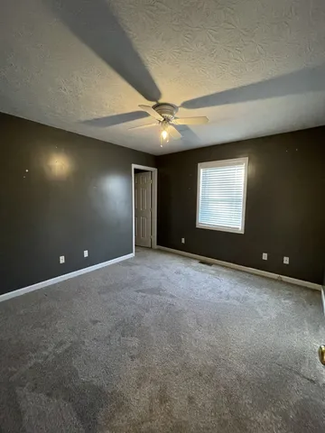a view of an empty room with a ceiling fan and window