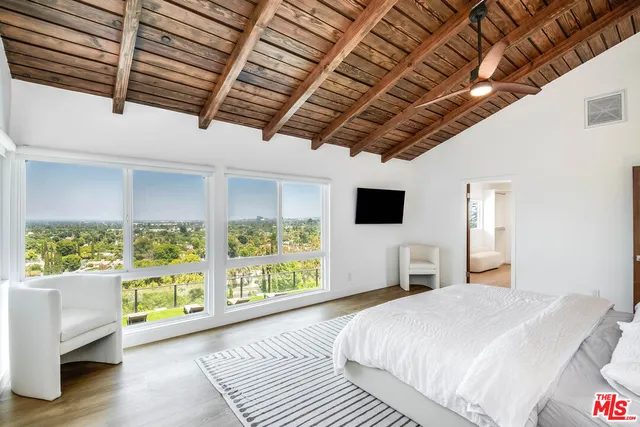 a bedroom with a large bed a flat tv screen and a fireplace with wooden floor