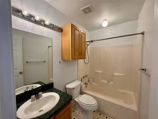 a bathroom with a granite countertop sink toilet a shower and a mirror