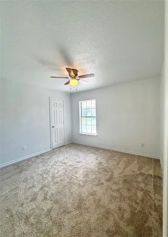 an empty room with windows and ceiling fan view