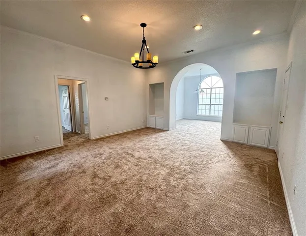 an empty room with a chandelier fan and wooden floor