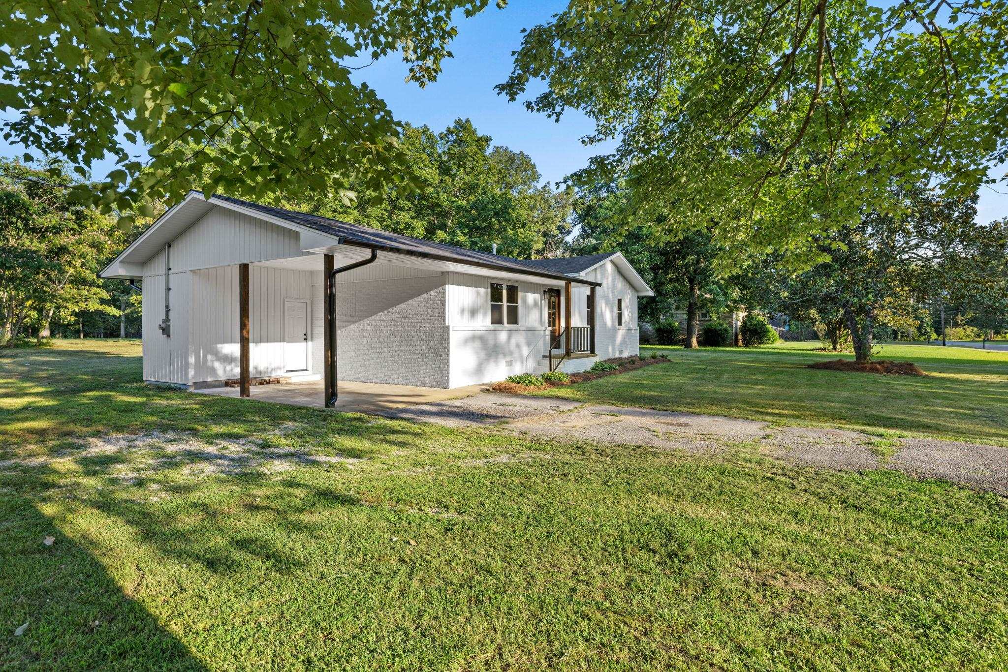 17 County Road 233 Corinth, MS 38834 - Photo 3 of 40 View of side of property with a yard, an attached carport, driveway, and view of wooded area