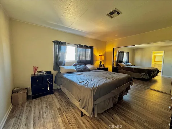 a spacious bedroom with a bed and wooden floor