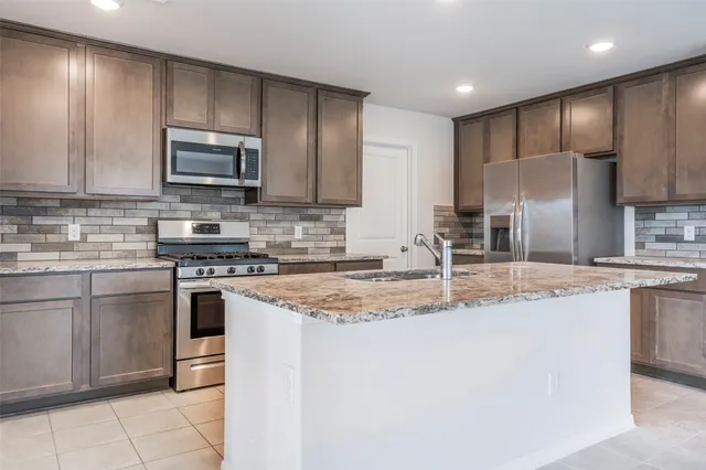 a kitchen with kitchen island a counter top space stainless steel appliances and cabinets