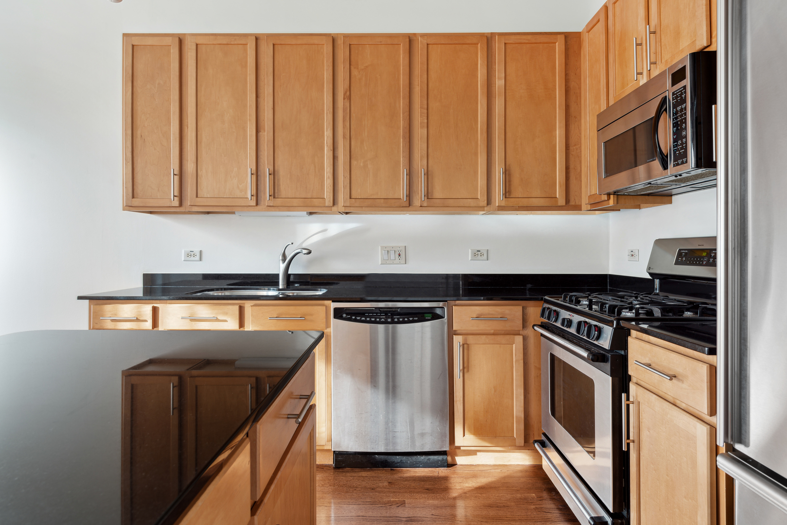 933 West Van Buren Street, Unit 824 Chicago, IL 60607 - Photo 7 of 18 a kitchen with stainless steel appliances granite countertop a stove a sink and a microwave