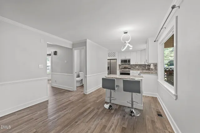 a kitchen with stainless steel appliances a refrigerator a stove a sink dishwasher and a dining table with wooden floor