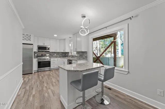 a kitchen with granite countertop a stove a sink dishwasher a refrigerator with wooden floor and cabinets