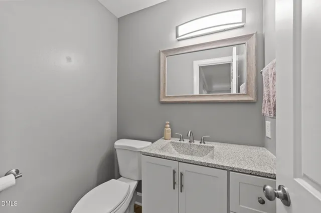 a bathroom with a toilet sink vanity and mirror