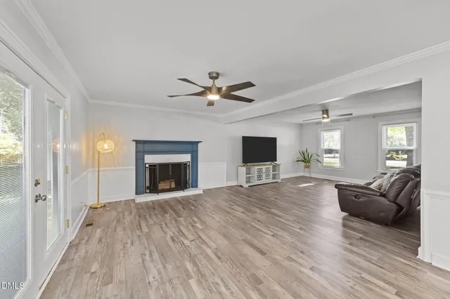 a view of a livingroom with a fireplace a ceiling fan and wooden floor