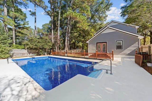 a view of house with backyard outdoor seating and trees in the background