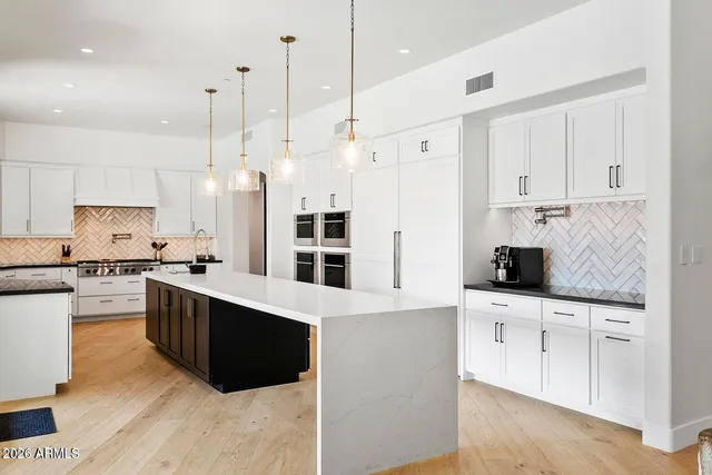 a kitchen with stainless steel appliances kitchen island granite countertop a sink and white cabinets
