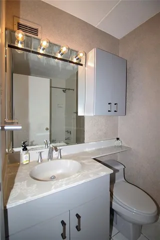 a bathroom with a granite countertop toilet sink and mirror