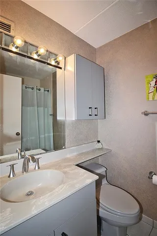 a bathroom with a granite countertop sink a toilet and a mirror