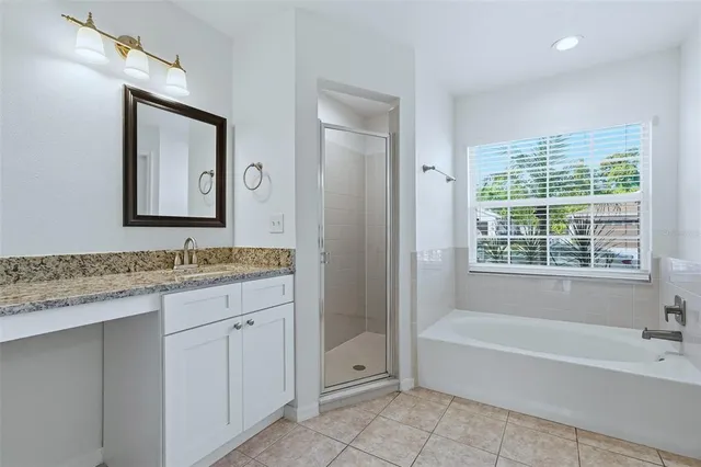 a bathroom with a granite countertop tub a sink and a shower