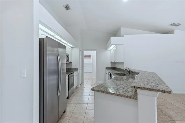 a kitchen with stainless steel appliances granite countertop a sink and a refrigerator