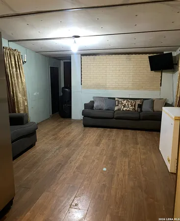 a living room with a couch and a potted plant on a wooden floor