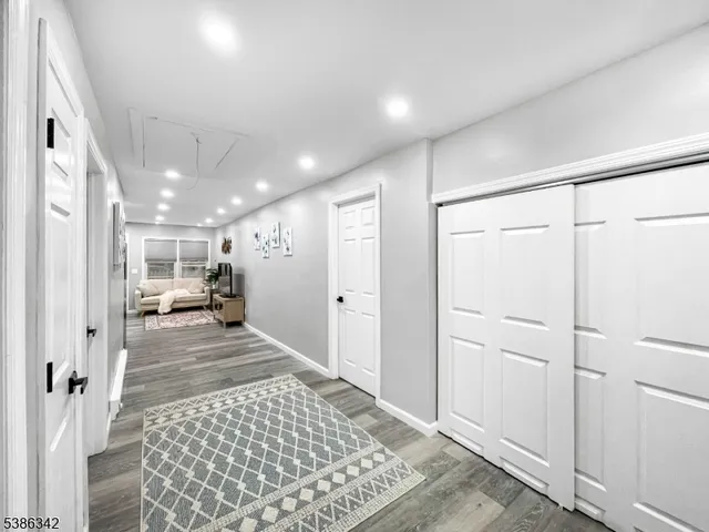 a view of a hallway with wooden floor and living room