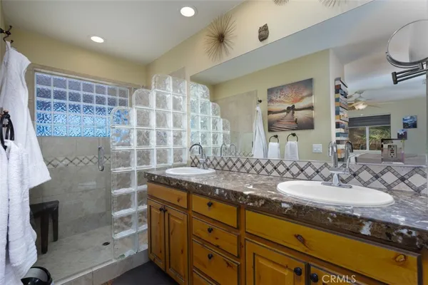 a bathroom with a granite countertop double vanity sink mirror and shower